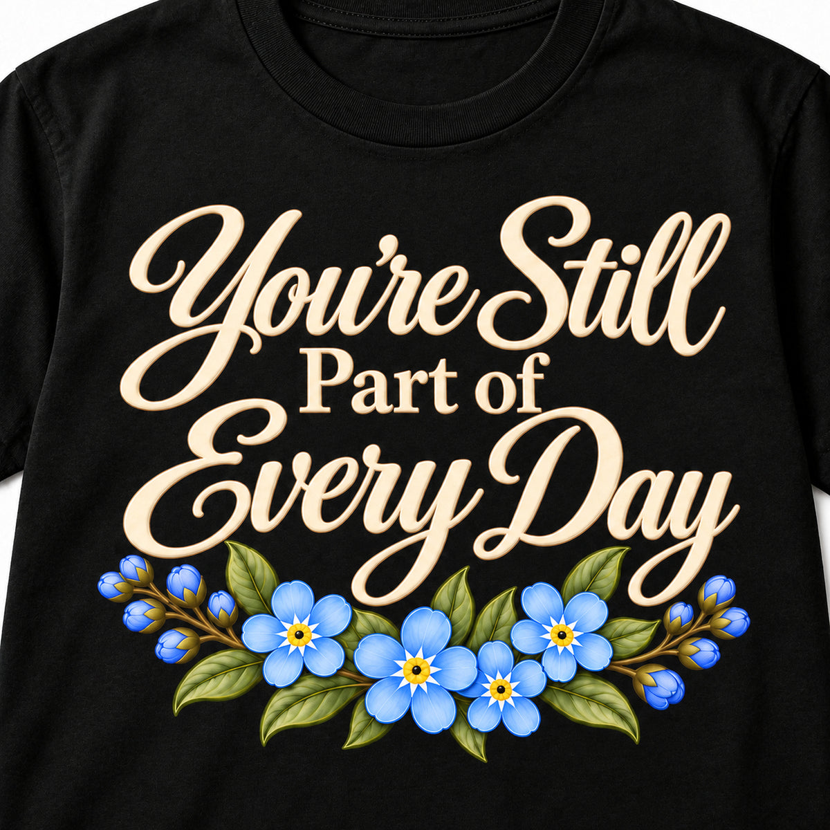 Closeup of the soft ivory lettering and blue forget-me-not flowers on the You're Still Part of Every Day T-shirt
